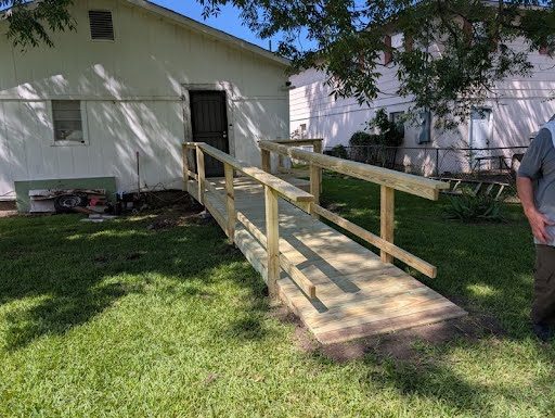 The finished ramp: fresh pressure-treated decking and handrails running from the back door out to the yard, ready to use.